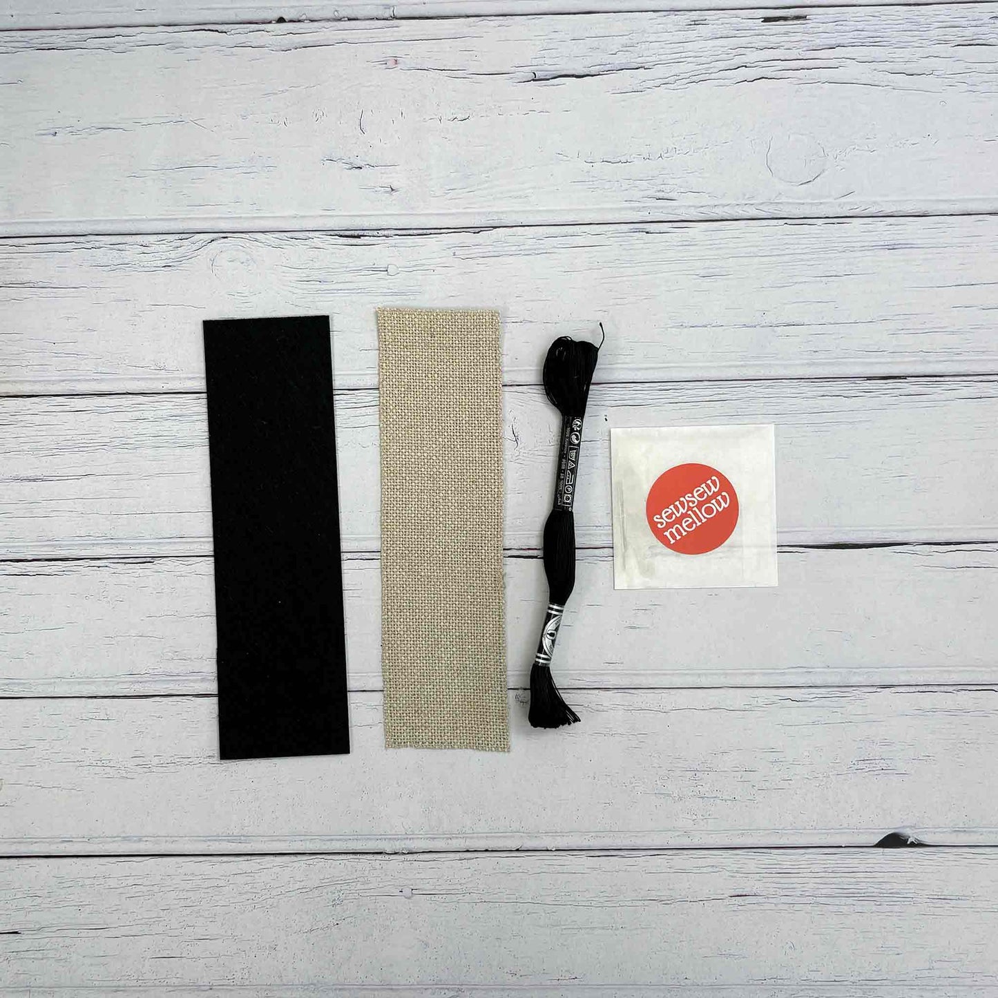 Blackwork Bookmark kit contents - black adhesive felt backing fabric, 7"x2" 20 holes per inch zweigart linen, black coton a broder, 2 tapestry needles, a needle threader
