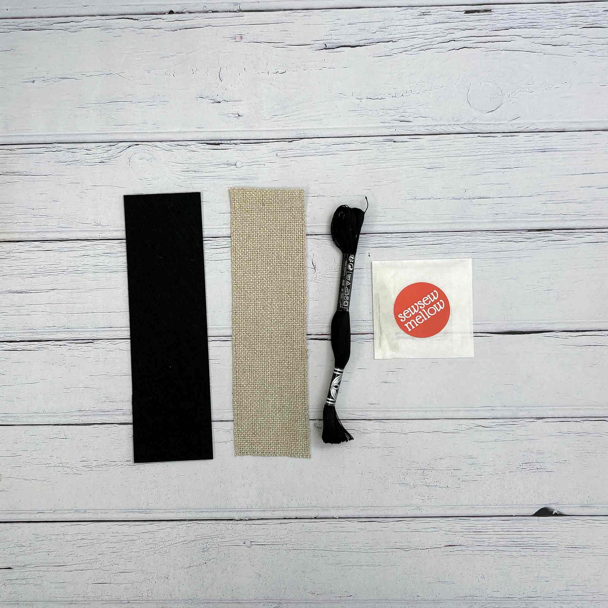 Blackwork Bookmark kit contents - black adhesive felt backing fabric, 7"x2" 20 holes per inch zweigart linen, black coton a broder, 2 tapestry needles, a needle threader

