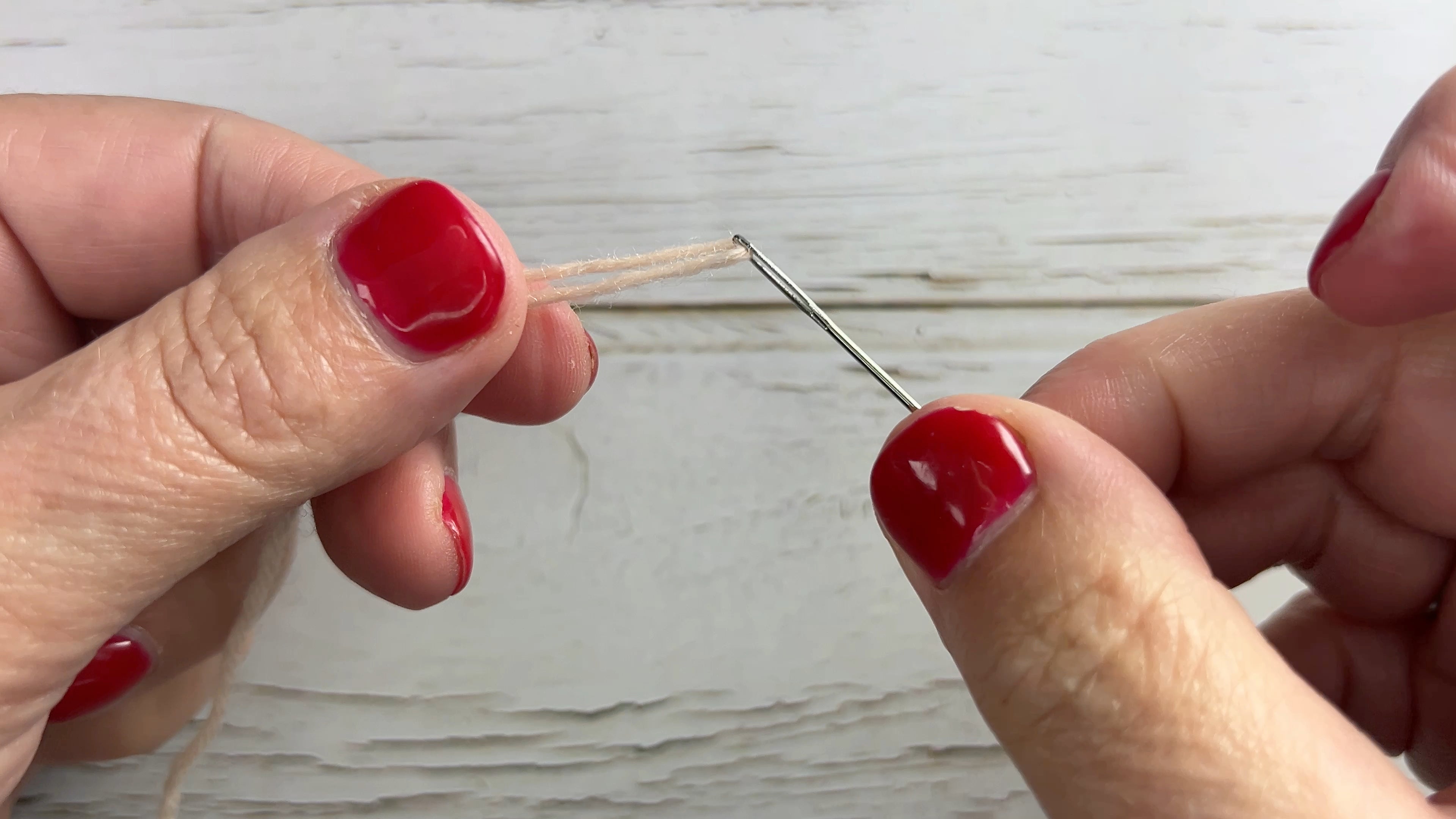 Load video: How to thread a tapestry needle with wool